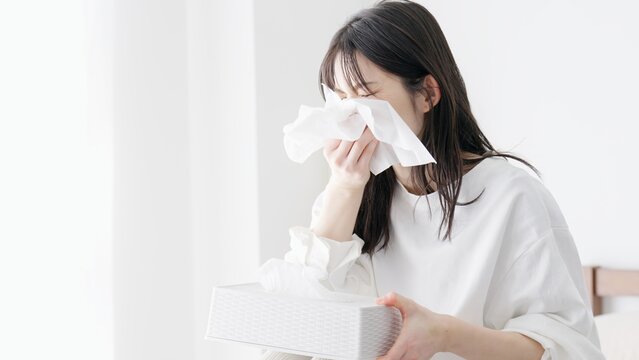 部屋で鼻をかむ女性