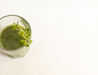green smoothie drink in a glass with microgreen top view, white background