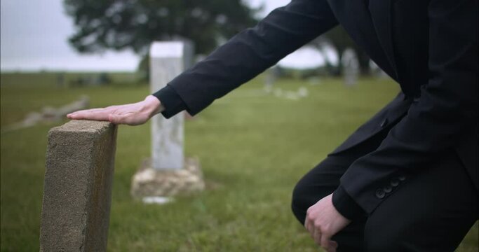 Sad, emotional man in cemetery grieving over death of loved one.