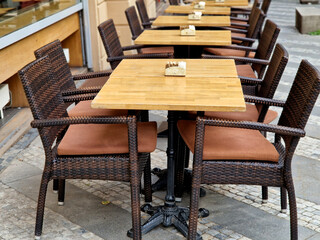 Cafe terrace with a wooden table and a flower in a tin pot. There must be blankets on the back to cover visitors caught in the cold. coffee on the autumn terrace, town square