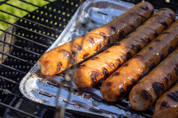 Bratwurst or hot dogs on grill. preparation of barbecue on sausage grill