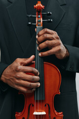 Closeup portrait of a man in a black suit holding a violin, focused on the elegant instrument in...