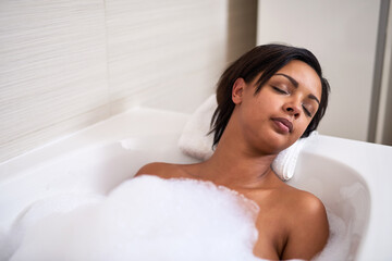 Bubble, bathtub and woman relax in bathroom for peace, calm and sleeping for beauty at home in the morning. Foam, girl and cleaning in water for skincare, wellness and hygiene health with eyes closed