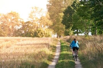 Obraz premium Woman on a bike is riding through rural scenery