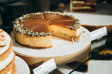 Pumpkin cheesecake sprinkled with pumpkin seeds on a cafe display. Traditional Thanksgiving cake.