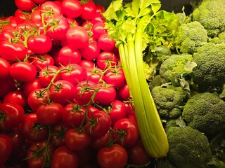Fresh red tomatoes with green celery and brocoli background
