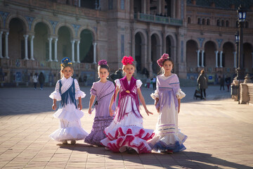 Four girls dancing flamenco, walking, in typical flamenco dress in a nice square in Seville. Dance...