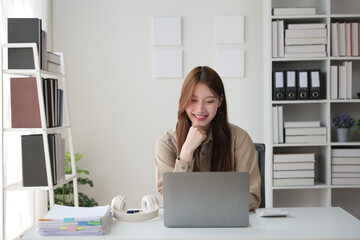 Young woman working indoor and using laptop with happy and smile face.