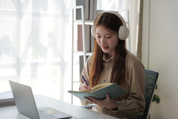 Young woman working indoor and using laptop, headset with happy and smile face.