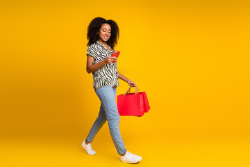 Photo of young woman addicted shopaholic curly hair in zebra print shirt and jeans strolling shopping mall isolated on yellow color background