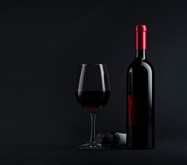 Glass with red wine and bottle next to it on a black background