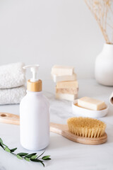 White cosmetic bottle with eucalyptus leaves on the background of bath accessories