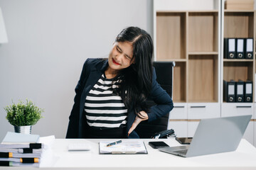 Overworked young Asian businesswoman office worker suffering from neck pain after had a long day at...