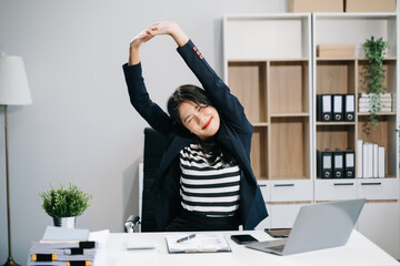 Overworked young Asian businesswoman office worker suffering from neck pain after had a long day at her office desk.