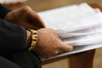 Priest in the black robe reading from the holy bible, close up.