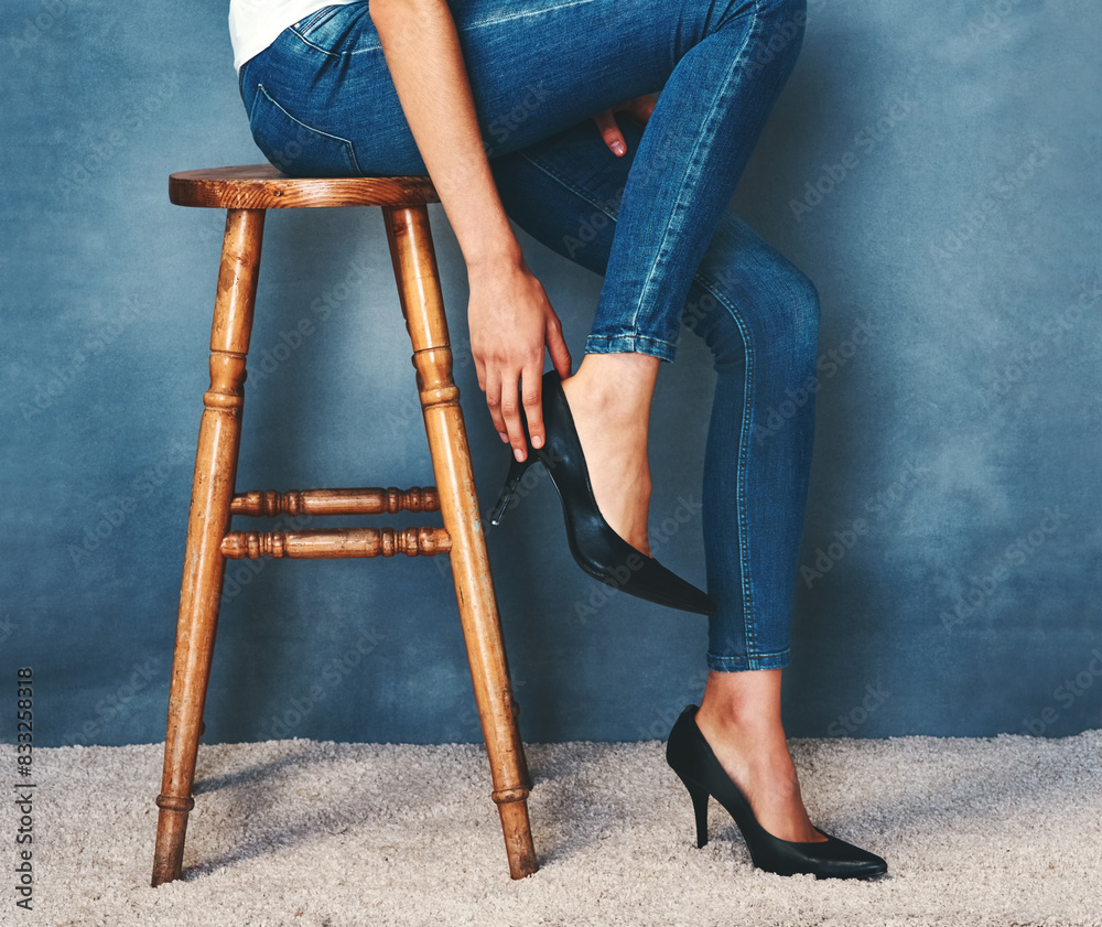 Canvas Prints Dressing, fashion and high heels with model on chair in studio for casual or trendy style. Feet, getting ready and shoes with person on blue background in denim jeans or stiletto footwear outfit