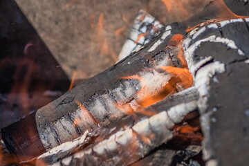 A close up of a log burning in a fire with flames emerging from