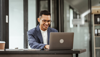 Middle-aged Asian businessman in formal suit working diligently at his desk. seasoned business and investment consultant, specializing in strategic portfolio management and financial analysis.