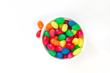 Mixed colorful jellybean sweets in a round bowl isolated on white with copy space