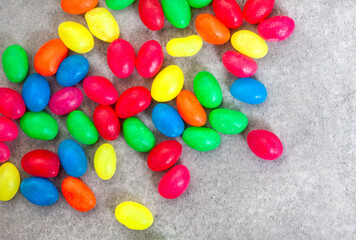 Mixed colorful jellybean sweets scattered on grey with copy space