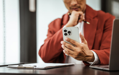 Middle-aged Asian businessman in formal suit working diligently at his desk. seasoned business and investment consultant, specializing in strategic portfolio management and financial analysis.