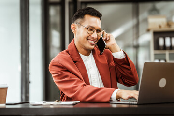 Middle-aged Asian businessman in formal suit working diligently at his desk. seasoned business and investment consultant, specializing in strategic portfolio management and financial analysis.