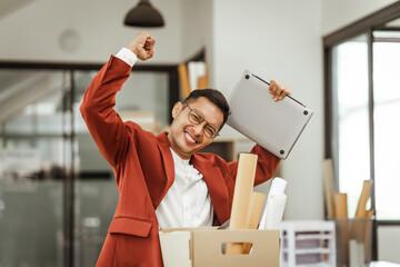 A middle-aged Asian businessman in a formal suit is working at his desk, preparing to resign after...