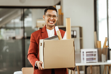 A middle-aged Asian businessman in a formal suit is working at his desk, preparing to resign after...