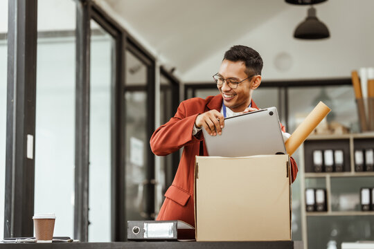 A middle-aged Asian businessman in a formal suit is working at his desk, preparing to resign after being laid off. He carefully reviews his resignation letter and finalizes the details.