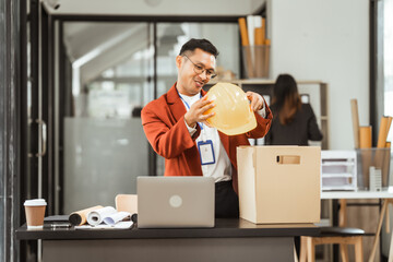 A middle-aged Asian businessman in a formal suit is working at his desk, preparing to resign after...