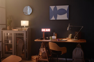Background image of dark teen bedroom interior with On air sign and minimal wooden desk copy space