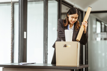 A young Asian businesswoman in a formal suit is working at her desk, preparing to resign after...