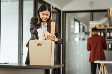A young Asian businesswoman in a formal suit is working at her desk, preparing to resign after...