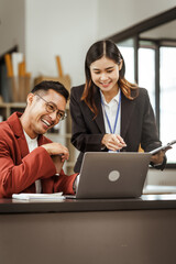 Middle-aged businessman and young Asian businesswoman work together at their desks, cooperation, collaboration, communication. teamwork, partnership, coordination to achieve mutual success.