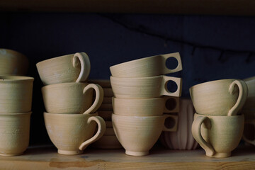 No people closeup of stacks of ceramic cups on shelf in pottery workshop