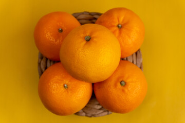 top view of five stacked oranges on straw plate isolated yellow background