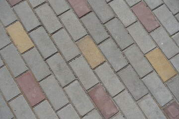 Texture of gray, pink and yellow concrete pavement with stretcher bond pattern