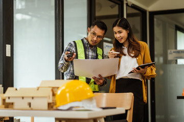 A middle-aged man, a young woman, and other Asian individuals collaborate on architectural engineering for condos and apartments, focusing on sustainable renovation and green energy solutions.