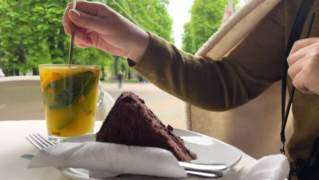 Prague chocolate cake and sea buckthorn tea in a restaurant, a girl eats a portioned piece