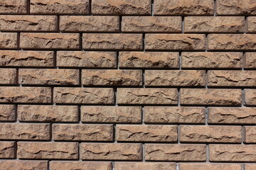 Textured surface of brown split face brick veneer wall with stretcher bond pattern