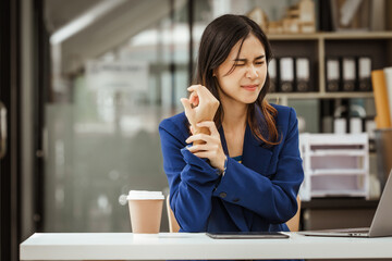 Young woman and other Asian individuals in formal suits work at desks with laptops, addressing concerns such as office syndrome, ergonomics, musculoskeletal disorders, and computer vision syndrome.