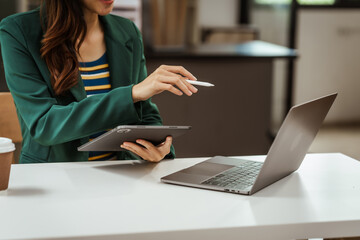 Young woman and other Asian individuals in formal suits working at desks with laptops. They engage in financial tasks including amortization, liquidity analysis, risk assessment, financial modeling.