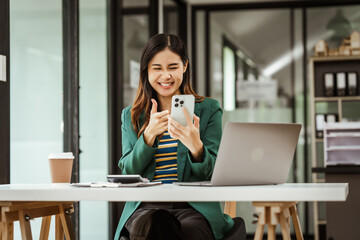 Young woman and other Asian individuals in formal suits working at desks with laptops. They engage in financial tasks including amortization, liquidity analysis, risk assessment, financial modeling.