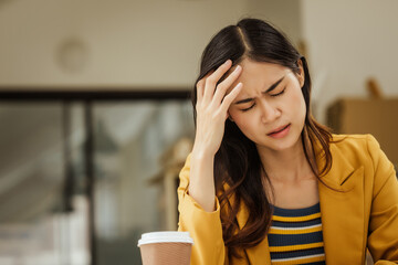 A young woman and other Asian individuals in formal suits are seen working at desks with laptops, facing challenges such as burnout, anxiety, pressure, fatigue, and job dissatisfaction.