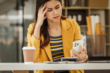 A young woman and other Asian individuals in formal suits are seen working at desks with laptops, facing challenges such as burnout, anxiety, pressure, fatigue, and job dissatisfaction.