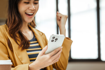 A young woman and other Asian individuals in formal suits are seen working at desks with laptops, portraying a successful and happy demeanor.