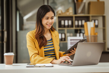 A young woman and other Asian individuals in formal suits are seen working at desks with laptops, portraying a successful and happy demeanor.