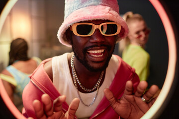 Closeup portrait of Black young man as hip-hop artist rapping to ring light and recording video for...