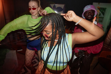 Dynamic high angle shot of multiethnic group of young people dancing with camera flash trendy Black young woman in foreground