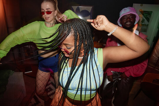 Dynamic high angle shot of multiethnic group of young people dancing with camera flash trendy Black young woman in foreground
